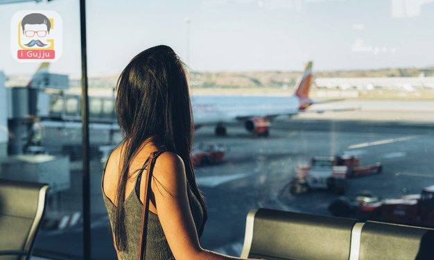 Woman tourist standing with luggage watching window at airport waiting his flight.