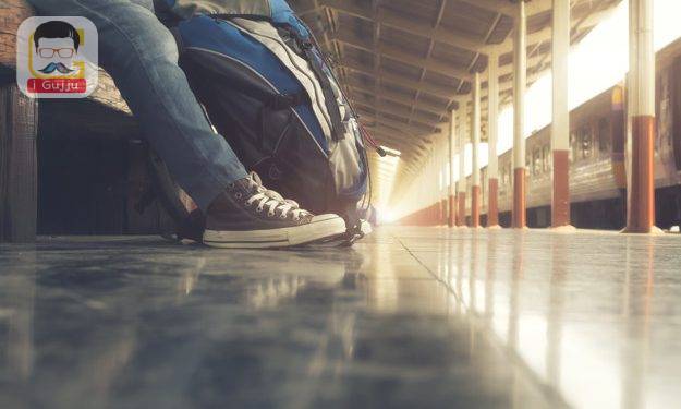 Traveler wearing backpack waiting for a train at trainstation and planing for next trip.Vintage tone, Retro filter effect, Soft focus, Low light.(selective focus)