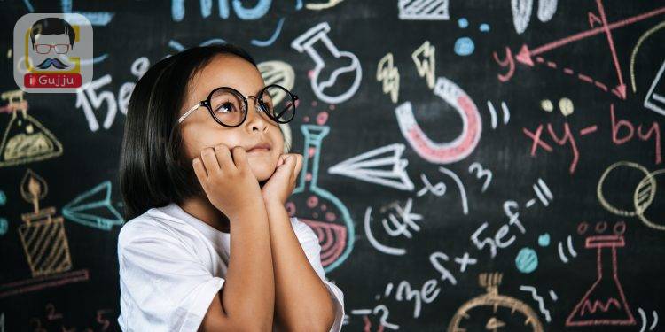 Portrait of happy little schoolchild wearing eyeglasses on background of backboard in school, smile and looking to camera in funny gesture