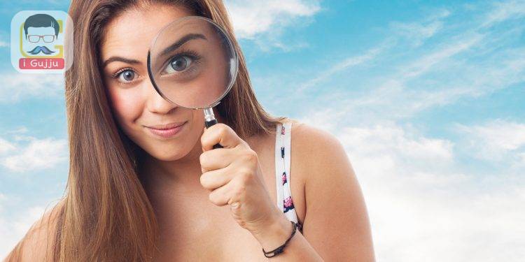 portrait of young woman looking through a magnifying glass