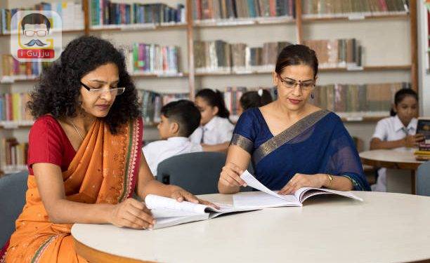 Two female teachers checking books in library while students are studying at school